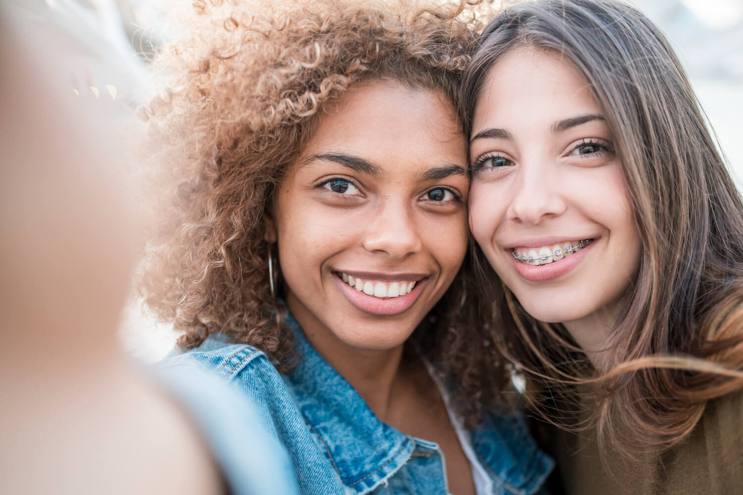 Duas jovens sorrindo, uma delas com aparelho fixo metálico, comparando tratamentos com alinhadores invisíveis em São Caetano do Sul.
