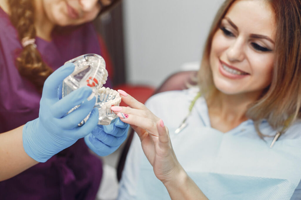 Dentista explica cirurgia com modelo anatômico para paciente interessada em implante zigomático na Clínica Perrella em São Caetano do Sul.