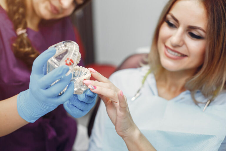 Dentista explica cirurgia com modelo anatômico para paciente interessada em implante zigomático na Clínica Perrella em São Caetano do Sul.