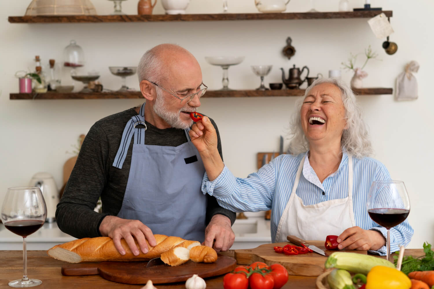 Casal de idosos sorrindo na cozinha, celebrando a reabilitação da arcada superior com implante zigomático na Clínica Perrella em São Caetano do Sul.