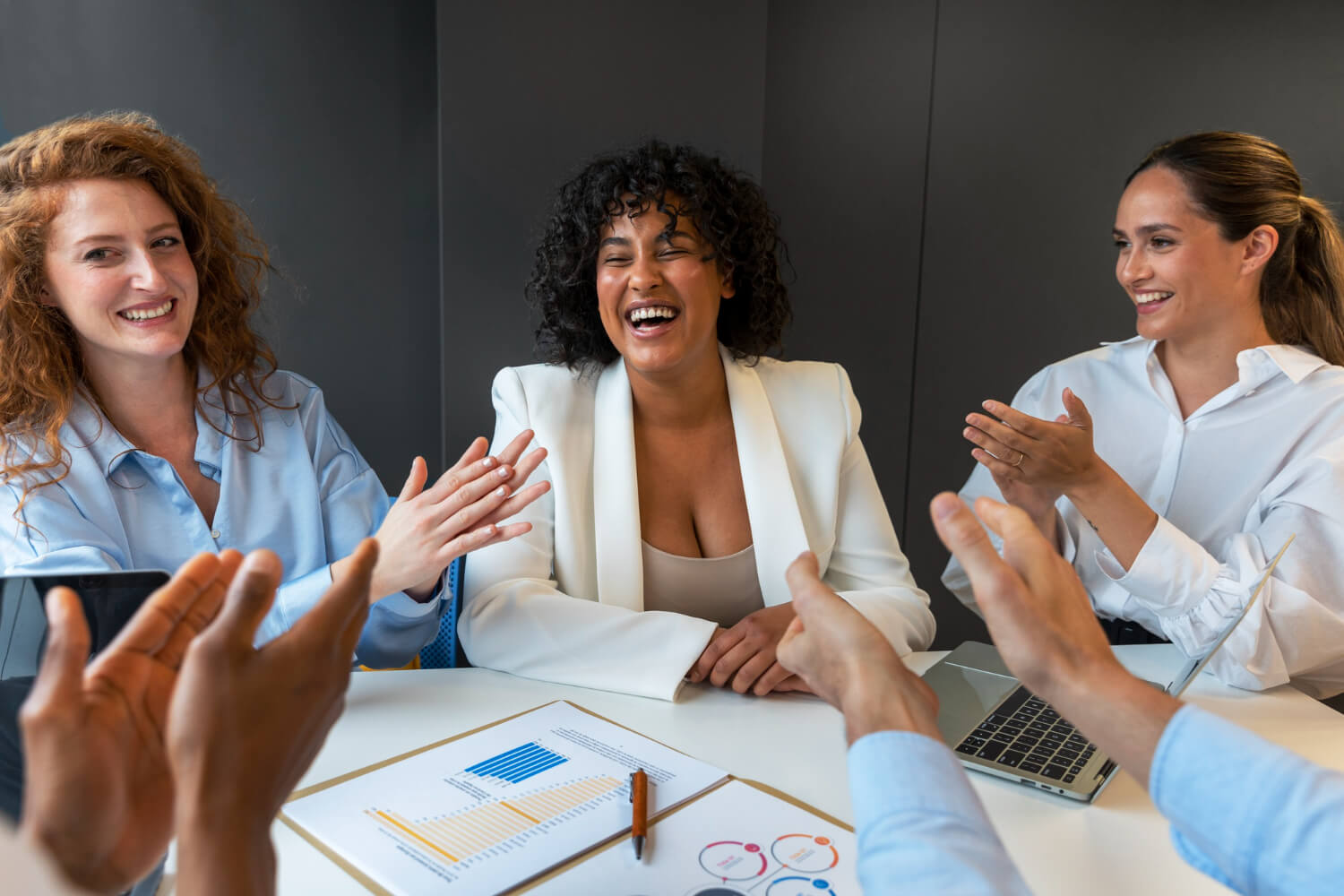 Mulheres em reunião corporativa sorrindo e aplaudindo, destacando a discrição e dicção com Invisalign na Clínica Perrella em São Caetano do Sul.