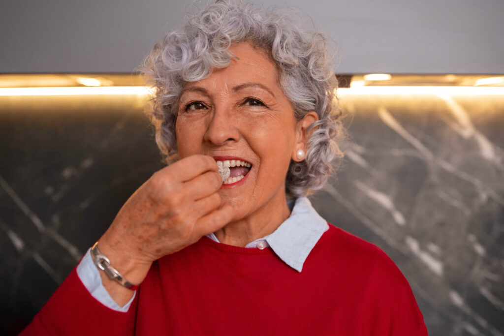Senhora sorridente mastigando com segurança após tratamento de dentes fixos sobre implantes na Clínica Perrella em São Caetano do Sul.